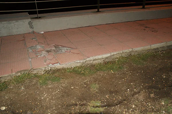 La loza de la vereda, rota por el colapso de la estructura. Al lado, una grieta en la tierra.