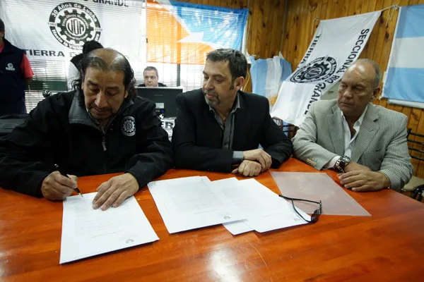 Firma el convenio Oscar Martínez. Lo observan Gustavo Zanone y Diego Boxer.