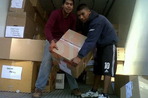 Dos vecinos de Berisso colaboran con la descarga de las donaciones.