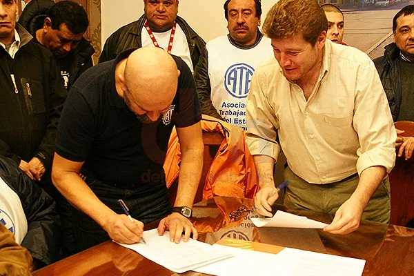 Firma Marcelo Córdoba; a su lado, Gustavo Melella.